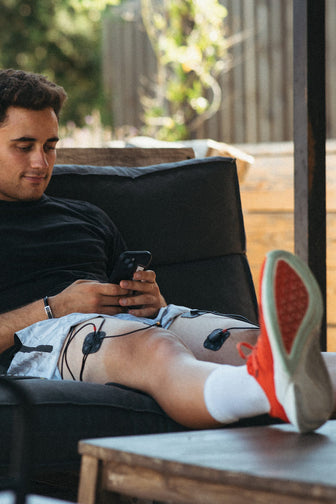A man using the Compex SP 4.0 EMS muscle stimulator for a quad muscle recovery session