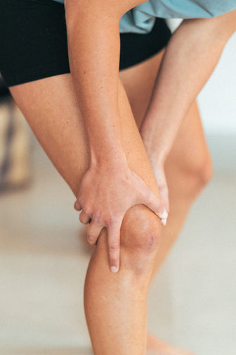 A woman holding her knee in discomfort