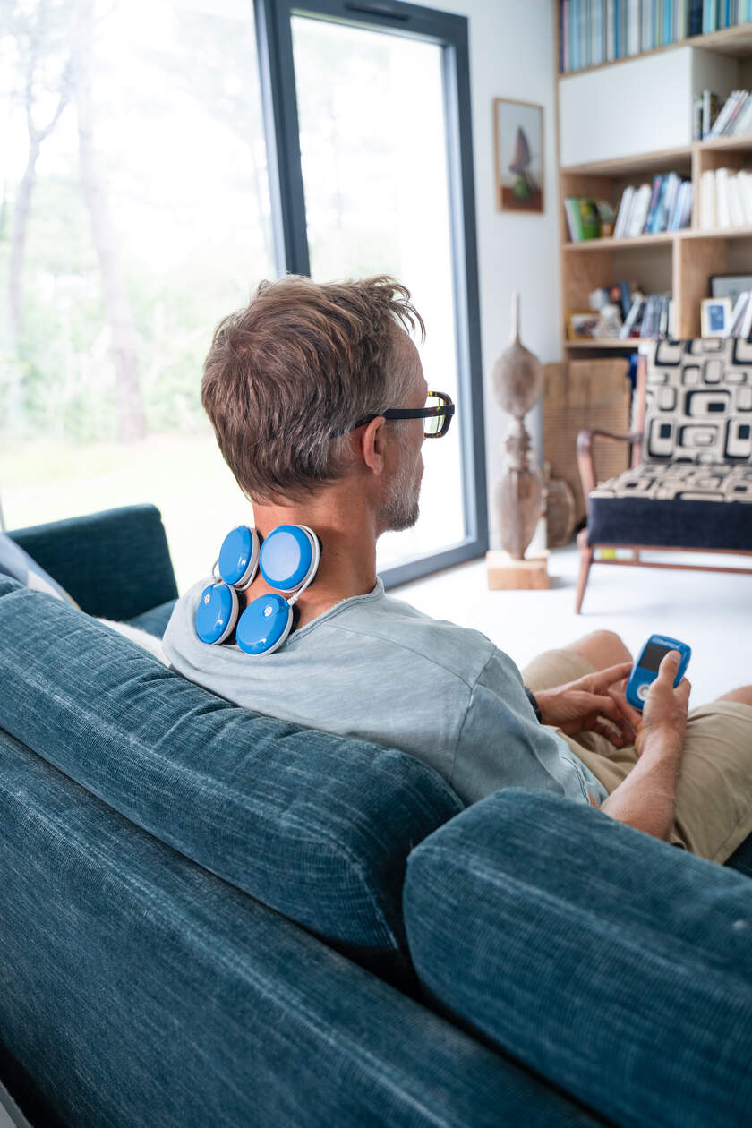 A man using the Compex FIT 5.0 EMS muscle stimulator to treat neck pain