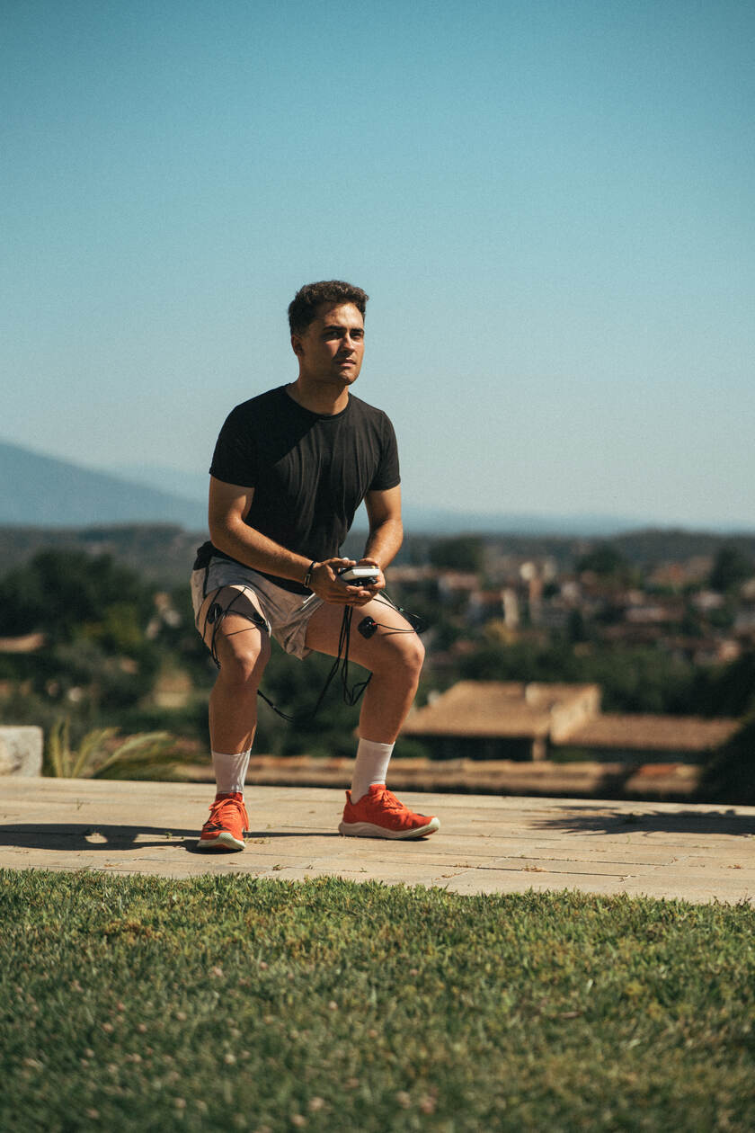 A man doing a squat using the Compex SP 4.0 EMS muscle stimulator