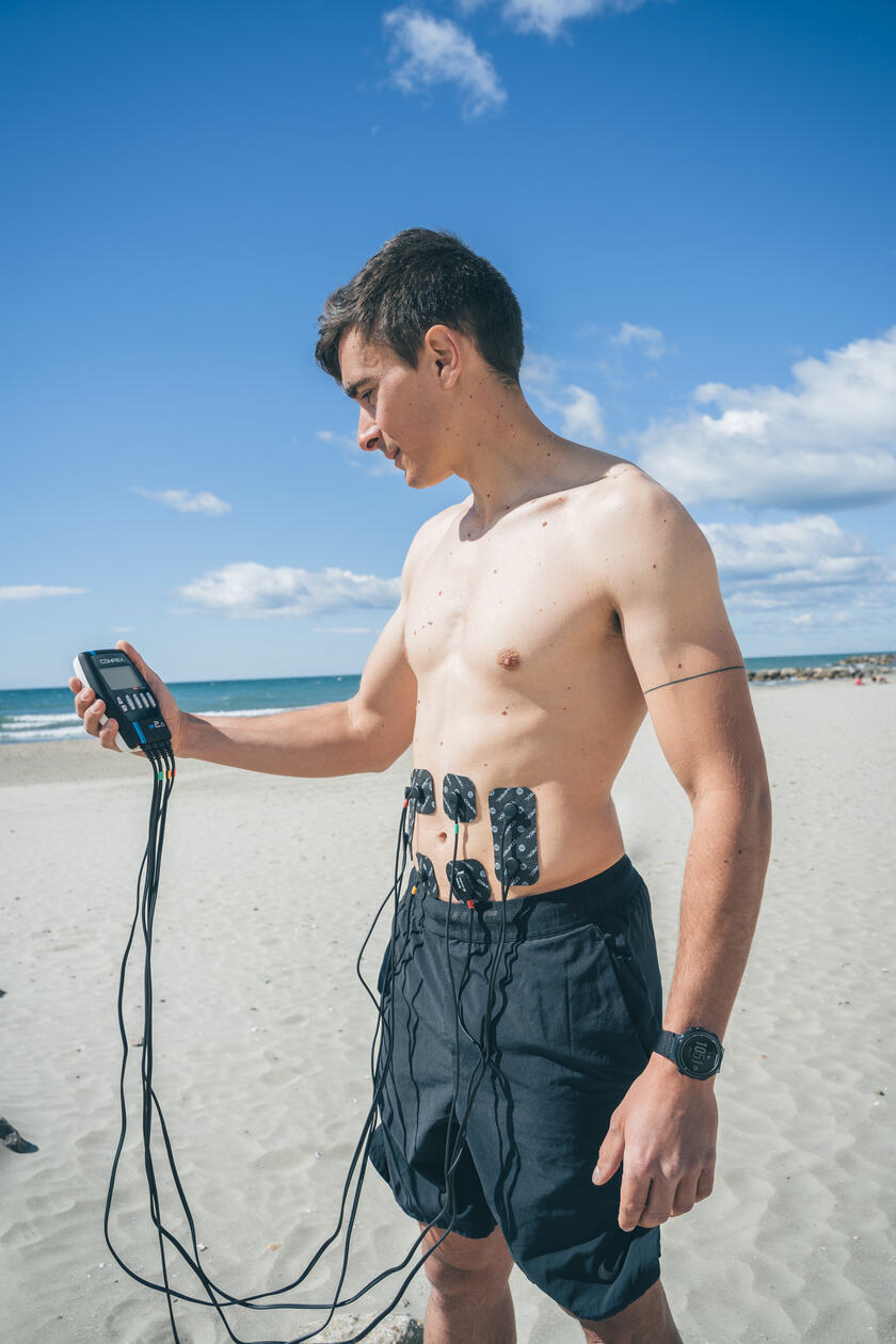 A man using the Compex SP 2.0 EMS muscle stimulator on his abs
