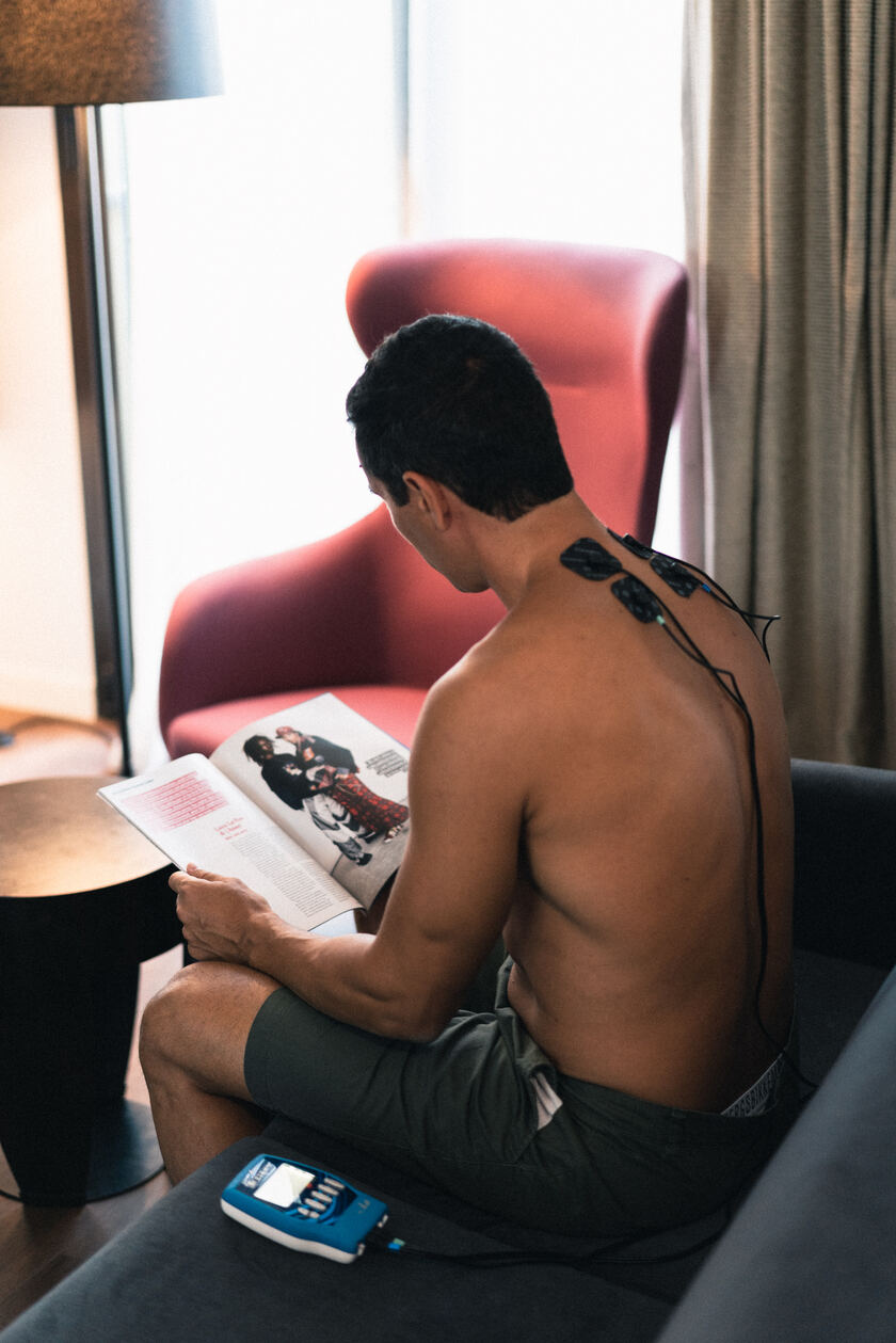 A man using the Compex FIT 1.0 EMS muscle stimulator to do recovery on his neck
